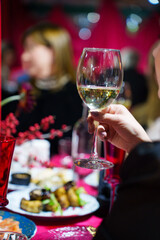 A glass of white wine or champagne in a woman's hand. 