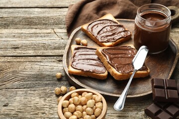 Tasty sandwiches with chocolate butter and hazelnuts on wooden table, closeup. Space for text