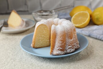 Delicious lemon cake with powdered sugar on light textured table, closeup