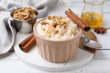 Tasty rice pudding with cinnamon served on white wooden table, closeup
