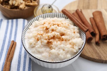 Tasty rice pudding with cinnamon served on white table, closeup