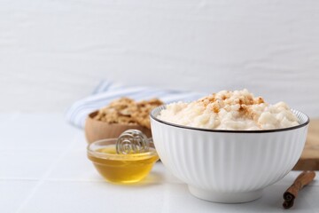 Tasty rice pudding with cinnamon served on white tiled table. Space for text