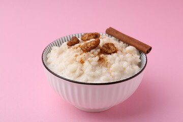 Delicious rice pudding with cinnamon and cashew nuts on pink background, closeup