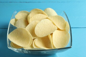 Tasty potato chips on blue wooden table, closeup