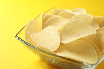 Tasty potato chips on yellow background, closeup