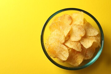 Tasty potato chips on yellow background, top view. Space for text