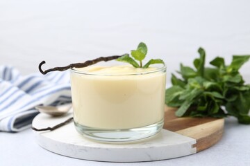 Tasty vanilla pudding, mint and pods on light grey table, closeup
