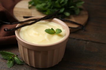 Tasty vanilla pudding, mint and pods on wooden table, closeup. Space for text