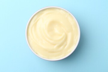 Tasty vanilla pudding on light blue background, top view