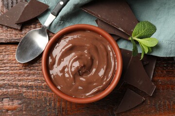 Tasty pudding with mint and pieces of chocolate served on wooden table, flat lay