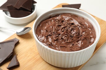 Tasty chocolate pudding in bowl served on white table, closeup