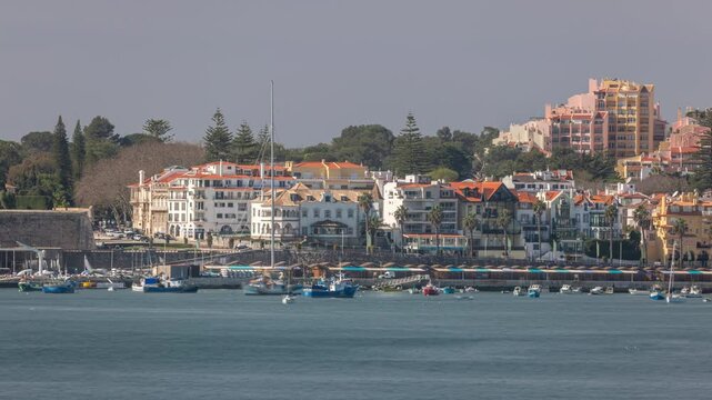 Boats and yachts floating on the water of Cascais bay with Palacete Seixas. Timelapse showcasing the scenic waterfront, historic architecture and coastal charm with houses and cranes in the background