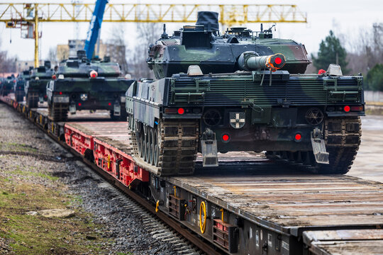 A convoy of German Leopard 2 main battle tanks loaded onto flatbed railway cars for military transport, highlighting strategic deployment and logistic