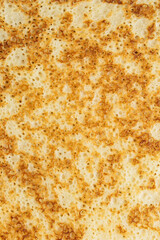 Close-up of a fried pancake or blin with holes for Maslenitsa or Shrovetide. Traditional Russian holiday dish for a feast. Macro photography