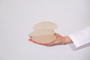 doctor holding breast enlargement implant in hands, plastic surgery concept, beauty enhancement,...