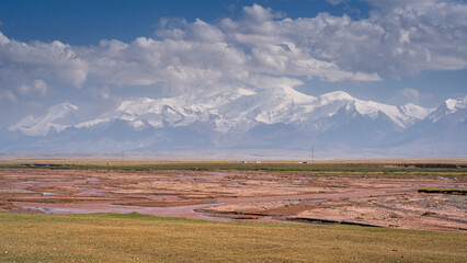 Colorful high altitude mountain landscape in Kyzyl Suu river valley with snowcapped Trans Alay range in background, Sary Tash, Kyrgyzstan Pamir