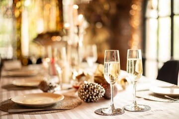 Elegant table setting with champagne glasses, festive new year decor, and warm lighting. Champagne, decor, and lighting create a celebratory atmosphere. Festive New Year gala dinner.