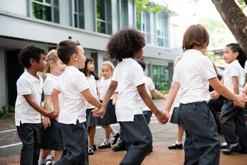 Group of diverse children holding hands in a circle outdoors. Children in school uniforms, playing and smiling. Happy students enjoying playtime together in a outdoor school. Diverse students © Rawpixel.com