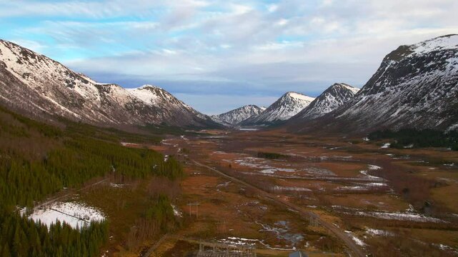 beautiful aerial shot through a winter valley with snowy mountains and blue sky on the scenic Vester&aring;len island in Norway