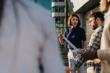 A group of professional business colleagues discuss plans and ideas on a rooftop terrace during...
