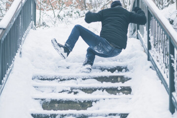 A person struggles to maintain balance on a steep set of snow-covered stairs, showing the challenges of winter weather in a suburban neighborhood. Generative AI