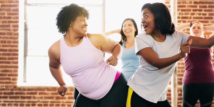 Diverse group of people in fitness dancing class. The fitness class features people dancing, smiling, and having fun. Diverse people exercising for well being. Diverse people training in a gym. - Powered by Adobe