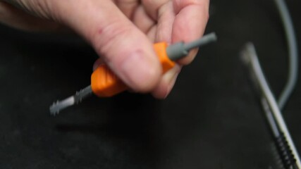 Master electrician removes insulation from wires. Minor electronics repair, man removes insulating layer from wire to repair, close-up.