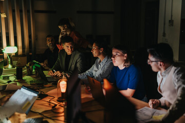 A diverse group of multigenerational business people working together late at night in an office setting, discussing strategies and solutions while immersed in a critical project meeting.