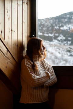 Redhead woman looking outside snowy window