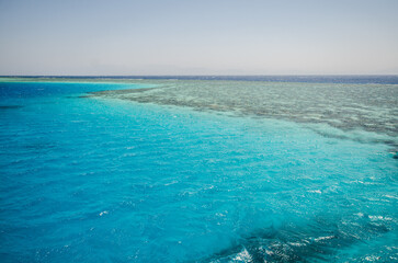 Aerial view of serene Red Sea showcasing vivid turquoise waters under clear skies. Tranquil waves create subtle patterns, meeting distant horizon