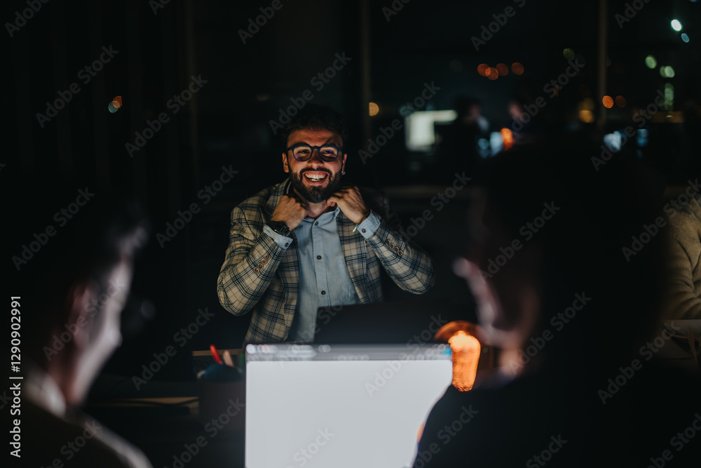 Wall mural Business professionals engaged in a positive discussion during a late-night meeting in a dimly lit office. The atmosphere is relaxed, and teamwork is evident among the colleagues discussing projects.