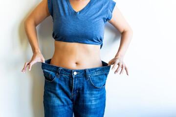 Woman showing weight loss by wearing old jeans