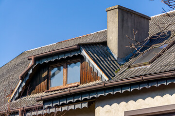 an old roof on a country house covered with asbestos tiles. asbestos on the roof a toxic roofing material. windows in the roof.