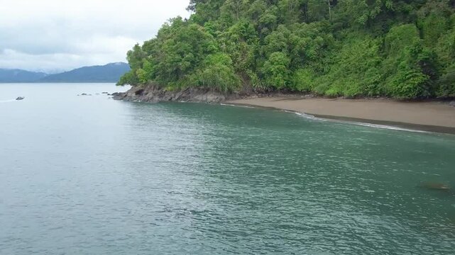 Drone footage of Davao Occidental and shoreline with green lush forest under a gray sky