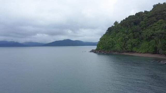 Drone footage of Davao Occidental and shoreline with green lush forest under a gray sky