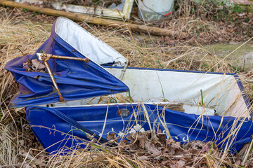 old antique baby carriage lying in the bushes next to an abandoned house. vandalized baby carriage.