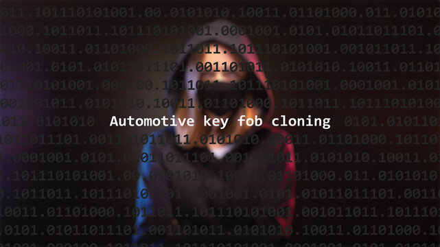 Cyber attack automotive key fob cloning text in foreground screen, anonymous hacker hidden with hoodie in the blurred background. Vulnerability text in binary system code on editor program.