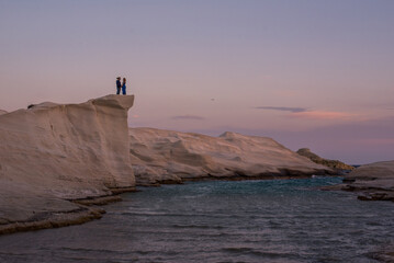 Anonymous couple standing on rock formations at Sarakiniko, Milos