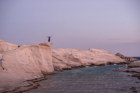 Anonymous woman celebrating on the cliffs at Sarakiniko, Milos