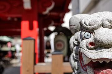 Temple protector - Close-up partial view Komainu's face in Japan, to emphasize furocity of temple's guarian loin. Bokeh background shows vivid red pillars of main gate and chochin paper lanterns.