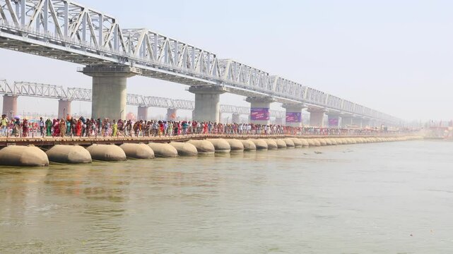 crowded people crossing pontoon bridge over ganges river at triveni sangam at mahakumbh
