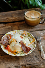 Fried eggs with bacon and yellow cherry tomatoes.