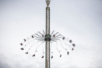 View of exhilarating swing and tower rides at an amusement park under an overcast sky, Munich, Germany.