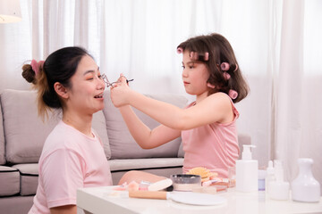 Asian mother and daughter share joyful bonding moment, explore makeup together, Take turns applying makeup,  young girl applies lipstick with mom while looking mirror,  learning, and warmth in home.