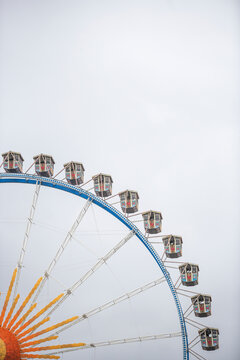 View of colorful ferris wheel at amusement park with panoramic skyline, Munich, Germany.