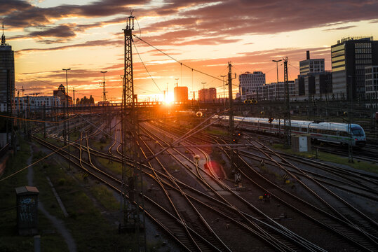 View of sunset cityscape with train tracks and modern architecture, Munich, Germany.