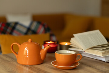 Cozy setting with tea, book, and candles in a warm ambiance