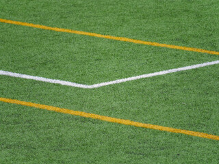 Close up of grass field with white and yellow lines in soccer field