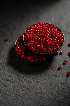 Top view of red peppercorns in a dark bowl on slate background