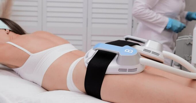 professional electrostimulation session, close up view o therapist applying EMS device on woman in modern clinic, muscle toning, body sculpting, fitness industry